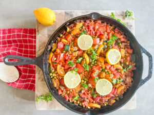 Vegetarian Paella Recipe, large pan of veggie paella garnished with parsley and lemon