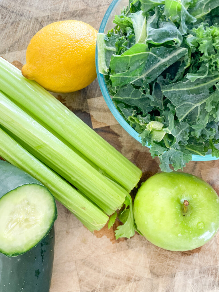 Kale Cooler Recipe, Kale, Celery, Lemon, Green Apple, and Cucumber on cutting board