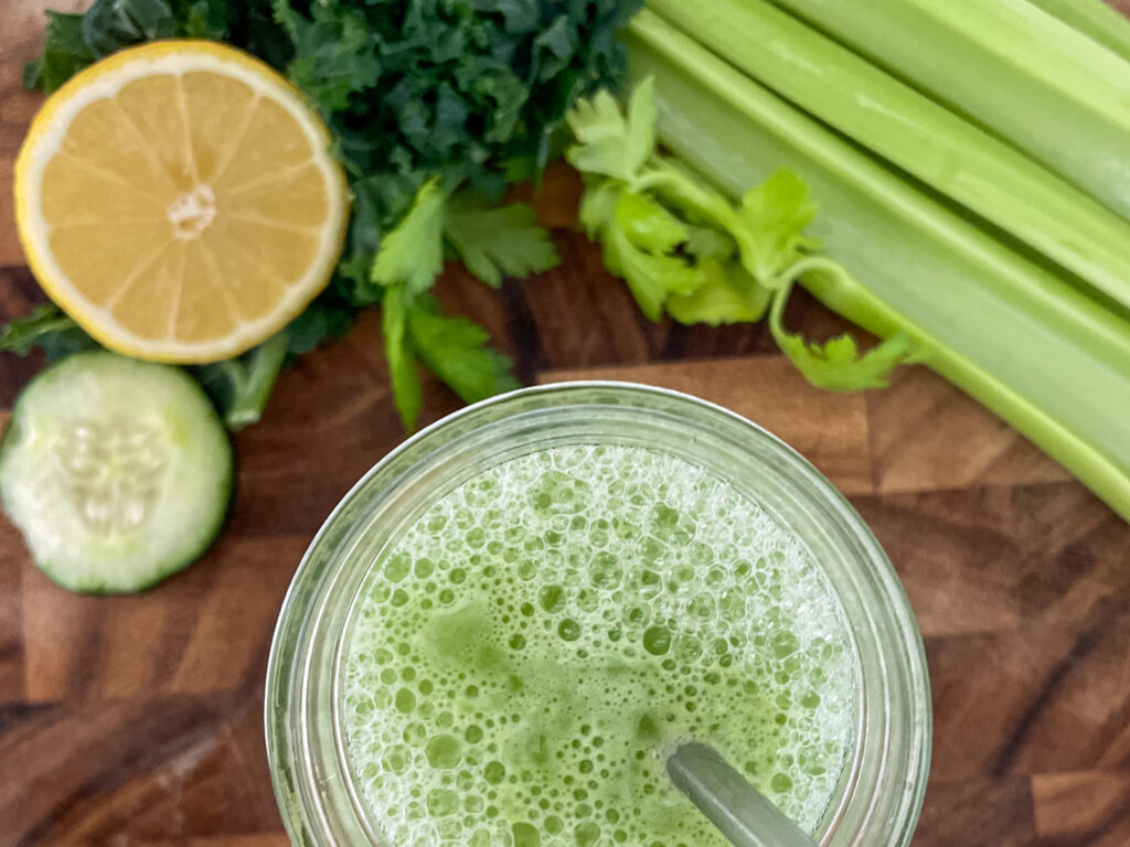 Kale Cooler Recipe, Green juice with straw and vegetables, celery, kale, lemon