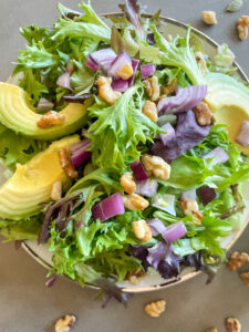 Mixed green salad with pepitas, onions, walnuts, and avocado